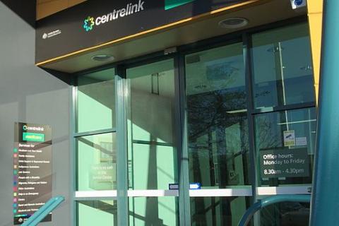 Glass sliding door entrance to a corporate building with text above door reading "CENTRELINK MEDICARE". 