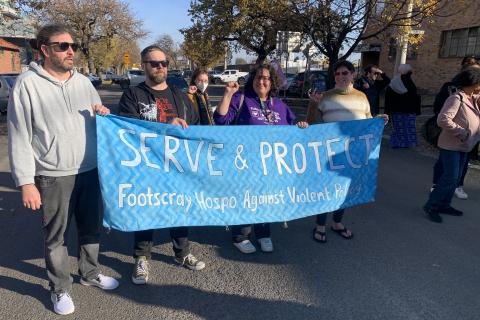 Footscray Hospo Workers Unite holding large blue banner with white font that reads ''Serve & Protect Footscray Hospo Against Violent Policing''