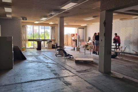 Inside the new Catalyst space, a stripped-back building interior with people doing work in the far right corner.