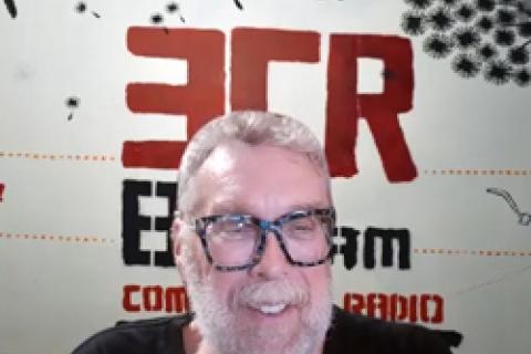 Indigenous Elder Uncle Paul sitting in front of 3CR Studio Wall