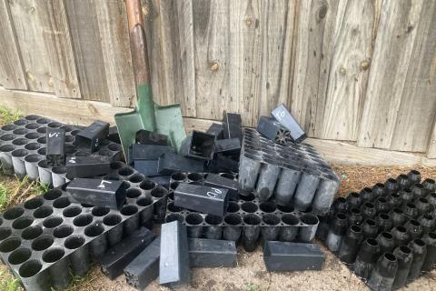 Shovel surrounded by black plastic pots. (Photo and staging by Amy, not a worksite photo).