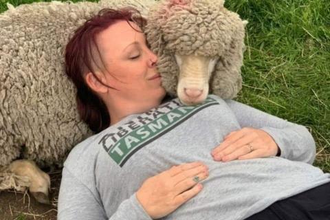 Photo of Kristy Alger reclining with a sheep