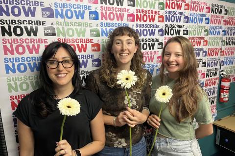 Photo of Jennifer, Savanna and Elise in the 3CR studio, each holding a flower.