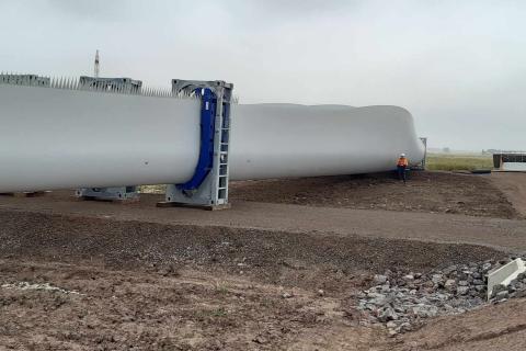 Our guest Michael standing next to the giant blade of a wind turbine. 