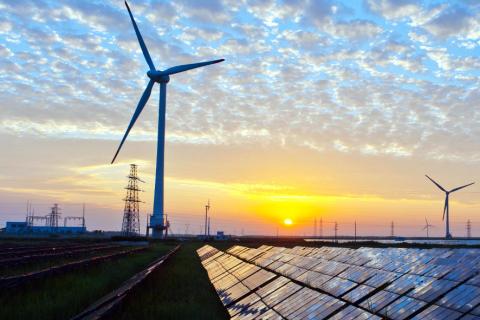 image of wind turbine and solar panels in landscape at sunset