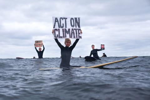 Surfers with an Act on Climate sign