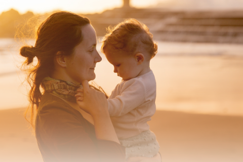 Mother and child at beach in hazy light. Mother has slightly worried expression.