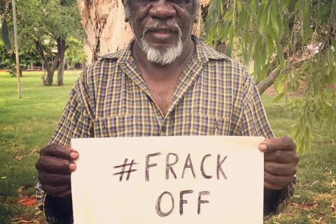 Mudburra Traditional Owner and Native Title Holder Ray Dimakarri Dixon from Marlinja NT holding a handwritten sign that says #frack off origin