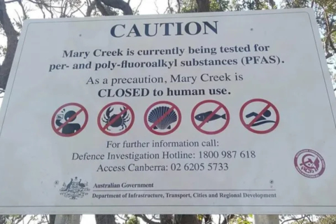 Photo of a Caution sign at Mary's Bay advising that Mary's creek is being tested for PFAS, and not to swim in the area, drink from the creek, or harvest seafood.
