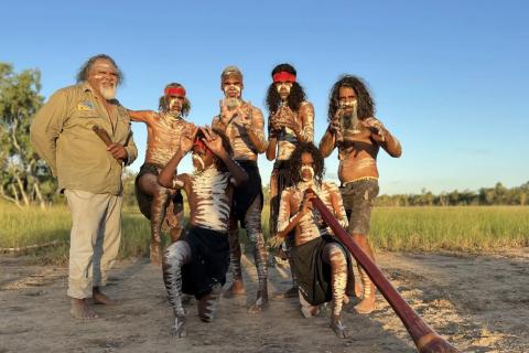 Five men painted in dance pose with digeridoo