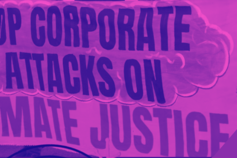 Colour-altered (pink and purple) photgraph of a protest banner reading 'Stop Corporate Attacks on Climate Justice'