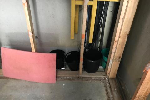A row of buckets lined up inside the wall of a retirement village unit to catch rainwater