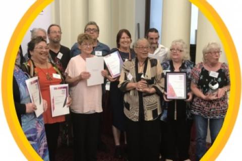 A group of older people holding up certificates they have been awarded
