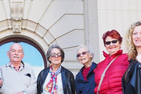 A group of older residents stand on the steps outside Parliament House