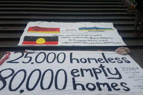 Photo of banners on the state library steps featuring the main one: 25,000 homeless, 80,000 empty homes in big text (in small text 35,000 in limbo on public housing waiting lists +100 every month). There are two other banners in the background, one has the Aboriginal flag and sovereignty never ceded as part of its text. 