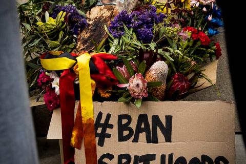 Ban Spithoods placard sits against a box of flowers, with a picture of Wayne Fella Morrison