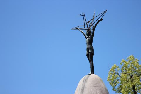 The Sadoko memorial in Hiroshima - a statue of a girl holding a metal crane, against a blue sky.