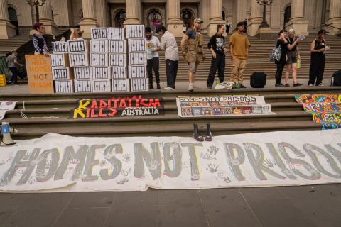 Banners laid on the steps of Parliament House saying FUND COMMUNITIES NOT PRISONS + POLICE from Homes Not Prisons' first rally, Naarm Oct 2022 Photo taken by Cathryn Murdoch)