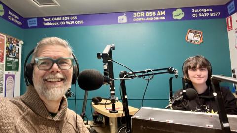 Amy and Keir sitting in the 3CR studio with their headphones on smiling for a sefie.