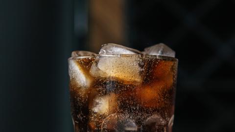 Cooling beverage with fizzy bubbles and ice cubes in a clear glass.