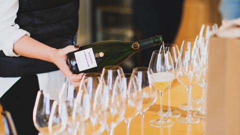 A person pours champagne in a glass