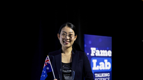 Tammy Lee holding an Australian flag and FameLab trophy