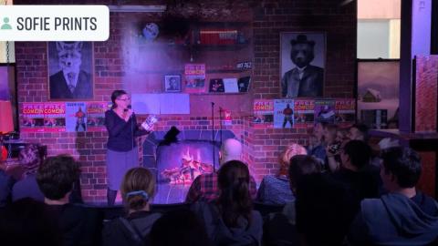 A comedian stands in front of a packed crowd. 