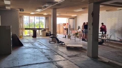 Inside the new Catalyst space, a stripped-back building interior with people doing work in the far right corner.