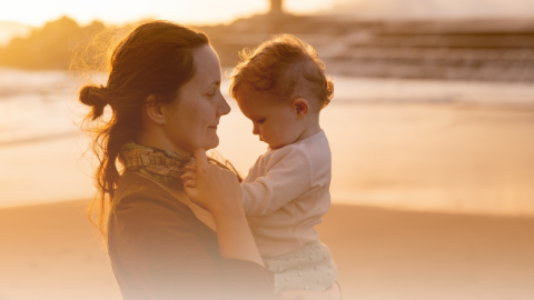 Mother and child at beach in hazy light. Mother has slightly worried expression.