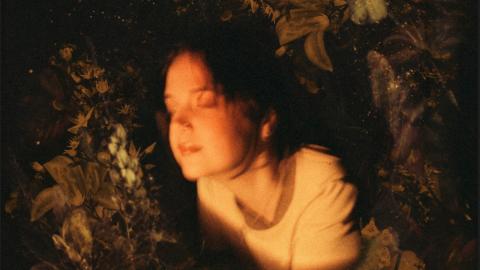 The album artwork for GLOW by Christobel, featuring a sepia toned image of a woman with her eyes closed surrounded by a wreath of flowers 