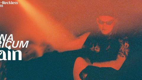 The album artwork for Villain, featuring a smoky orange and black background with the artist Simona Castricum in front wearing black sunglasses