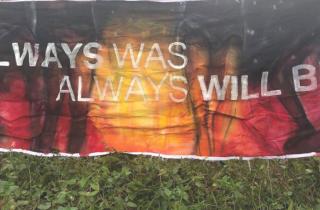 A banner that's painted in the aboriginal flag colours. The banner says Always Was Always Will Be